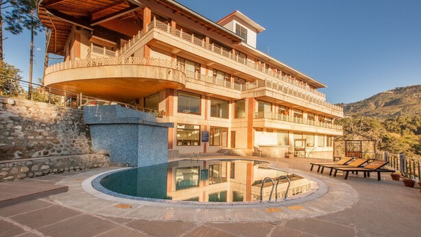 A multi-story building with a pool, balconies, and a stone wall. - Aamod @ Bhimtal (Nainital)