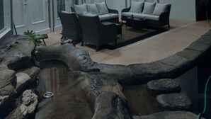 Un espace patio intérieur comprenant deux canapés, un ventilateur de plafond et une petite fontaine.