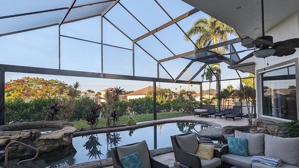 Une vaste terrasse extérieure dotée d’une piscine, de coins salon et offrant une vue sur un jardin aménagé.