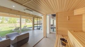 Un espace de bien-être moderne avec des bancs en bois, un sauna et un mur de verre donnant sur un espace extérieur verdoyant.