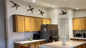 Una cocina con armarios de madera, una isla central, un refrigerador, un microondas y una cafetera.