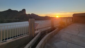 Vista del atardecer desde una terraza en la azotea, con barandilla de metal y suelo de hormigón.