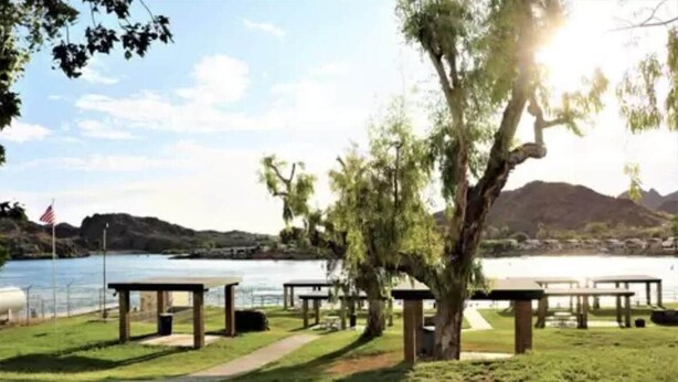 Un parque junto al lago con mesas de picnic y una bandera.
