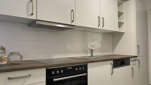 Una cucina moderna con mobili bianchi, una cappa in acciaio inossidabile, forno integrato e un piano di lavoro in legno.