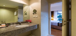 A hotel bathroom with a granite countertop sink, a mirror, and a small flower arrangement. - RCG Suites Pattaya (Pattaya)