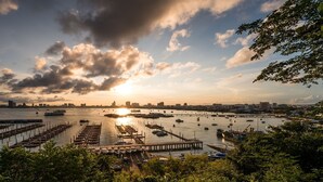 A marina with boats docked, a city skyline in the background, and a sunset. - RCG Suites Pattaya (Pattaya)