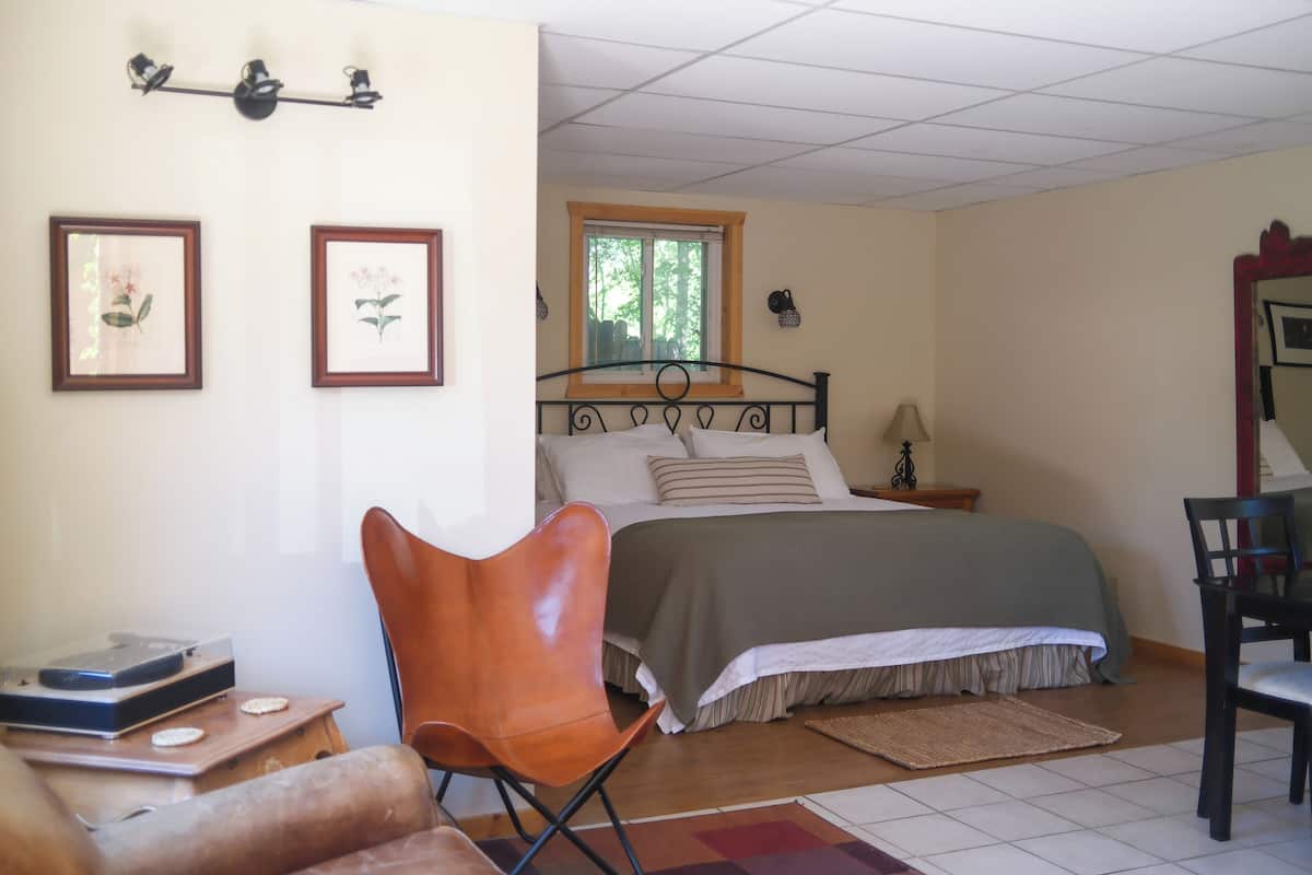 A bedroom with a bed, a chair, a desk, and a window.