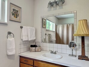 Bathroom with a window offering a view of lush greenery, featuring a bathtub, sink, and ample storage.