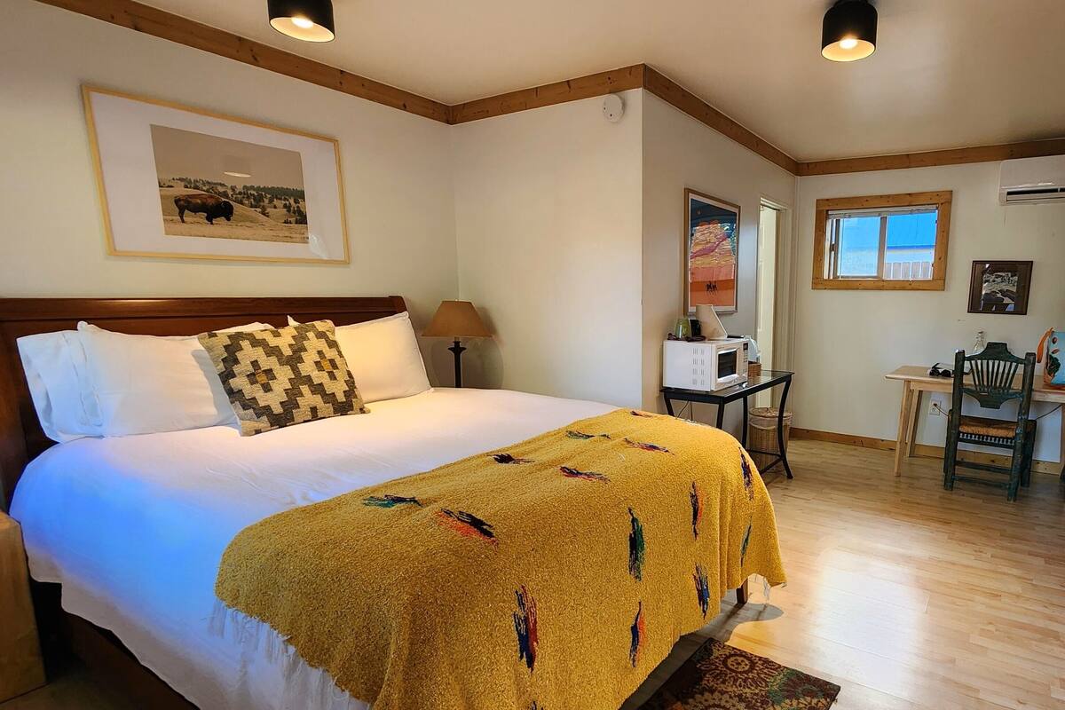 A hotel room with a large bed, a desk, a chair, and a window.