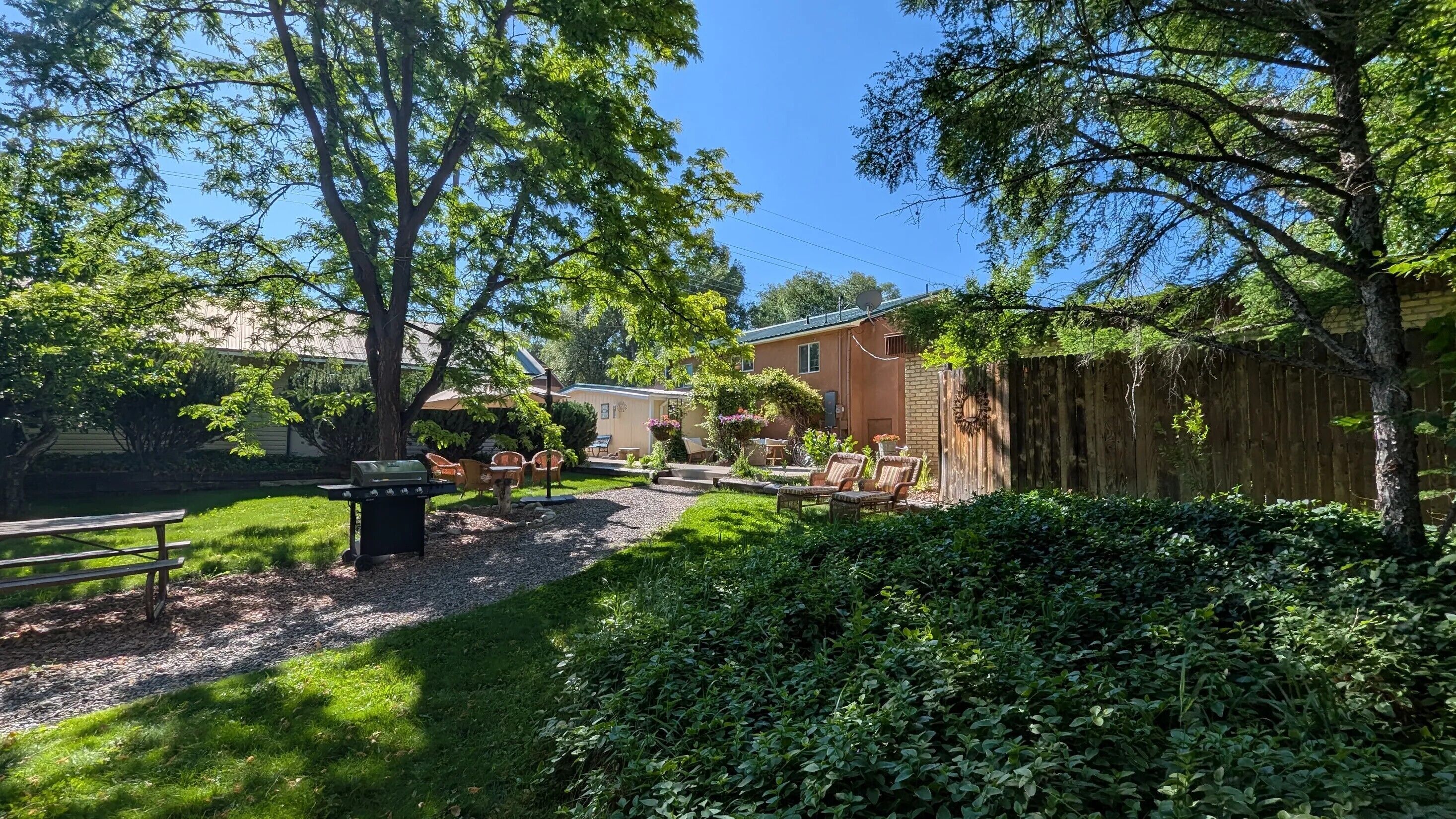 A backyard with a barbecue grill, outdoor furniture, and a wooden fence.