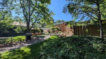 A backyard with a barbecue grill, outdoor furniture, and a wooden fence.
