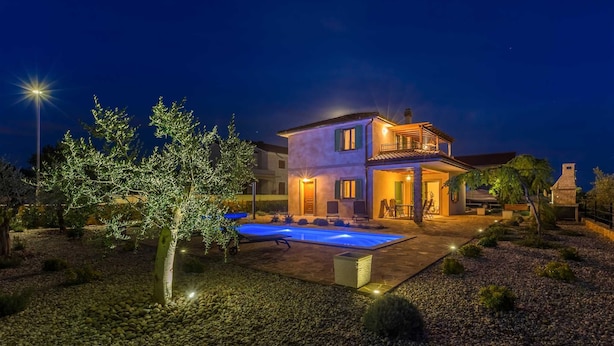 A two-story house with a swimming pool, outdoor seating, and a well-lit garden at night. - Rustic Villa BELLAMARE with pool (Linardići)