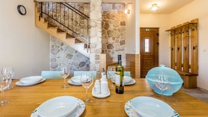 A dining area with a wooden table set for four, surrounded by stone walls and a staircase. - Rustic Villa BELLAMARE with pool (Linardići)