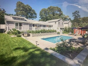 A two-story house with a swimming pool, a covered patio, and a fenced yard.