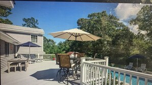 A deck with a pool, outdoor furniture, and a view of the surrounding trees. - In Sag Harbor Village. Walk to town, and less than 1/2 mile to Havens Beach. (Sag Harbor)