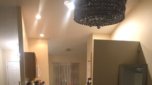 A compact living space with a kitchenette, a large mirror, and a seating area with two stools. - 3 Bedroom/2 Bathroom Home with Enclosed Porch (Sleeps 5-6) (Davenport)