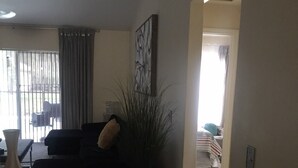 A living room with a sofa, a potted plant, and a painting on the wall. - 3 Bedroom/2 Bathroom Home with Enclosed Porch (Sleeps 5-6) (Davenport)