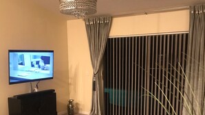 A living room with a flat-screen TV, a black coffee table, a laptop, and a decorative lamp. - 3 Bedroom/2 Bathroom Home with Enclosed Porch (Sleeps 5-6) (Davenport)