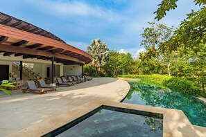 A poolside area with lounge chairs, a covered seating area, and a clear view of the pool. - Reserva Conchal Resort - Carao Complex (Cabo Velas)