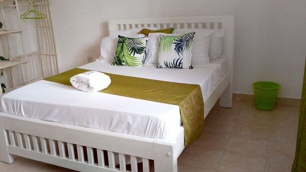 A bedroom with a white bed, a green throw blanket, and a white crib. - White House Mtwapa (Mtwapa)