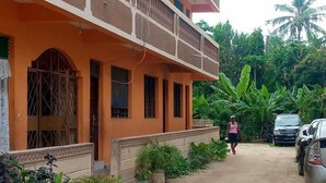 A multi-story building with balconies, a dirt pathway, and parked cars. - White House Mtwapa (Mtwapa)