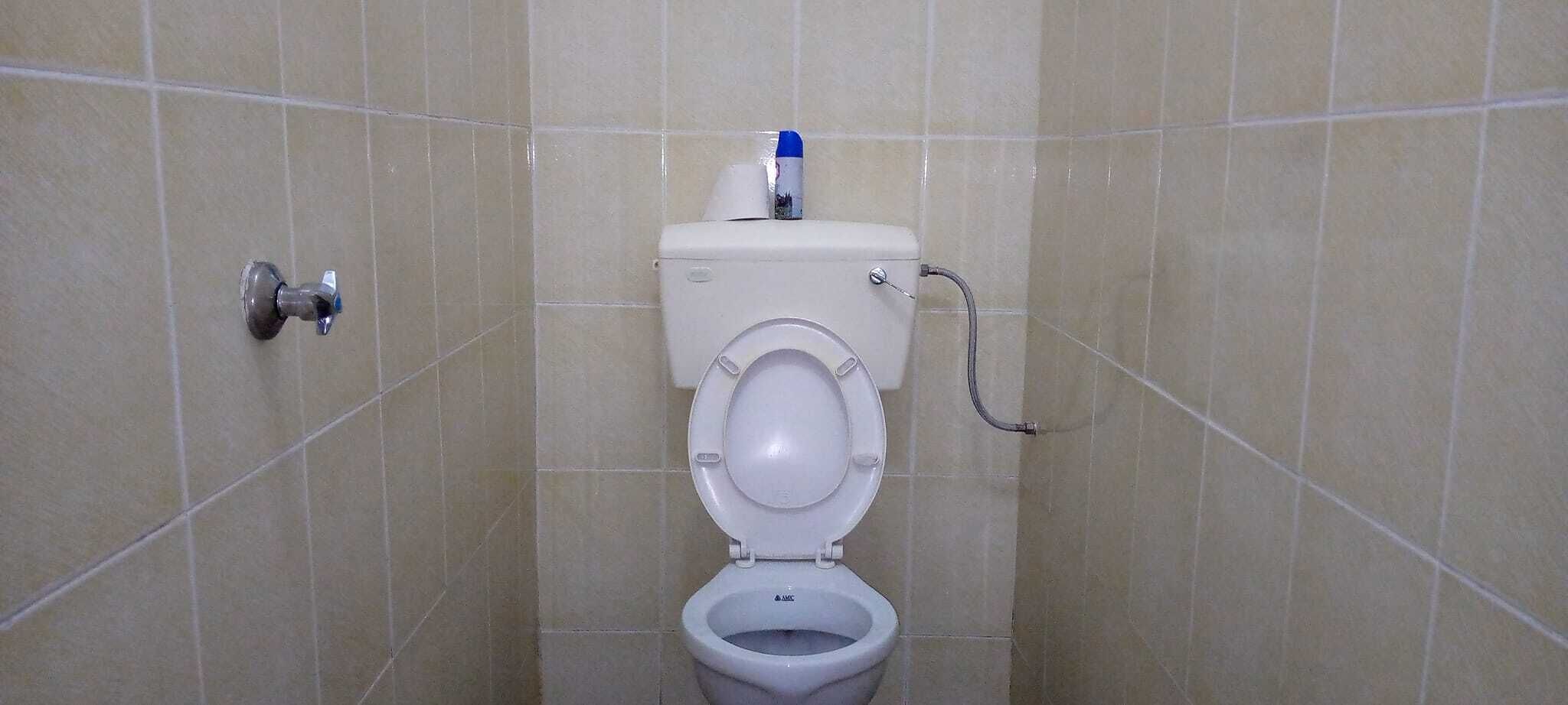 A standard bathroom with a toilet, a hand dryer, and a paper towel dispenser.
