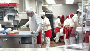 Una cucina professionale con elettrodomestici in acciaio inossidabile e personale in divisa.