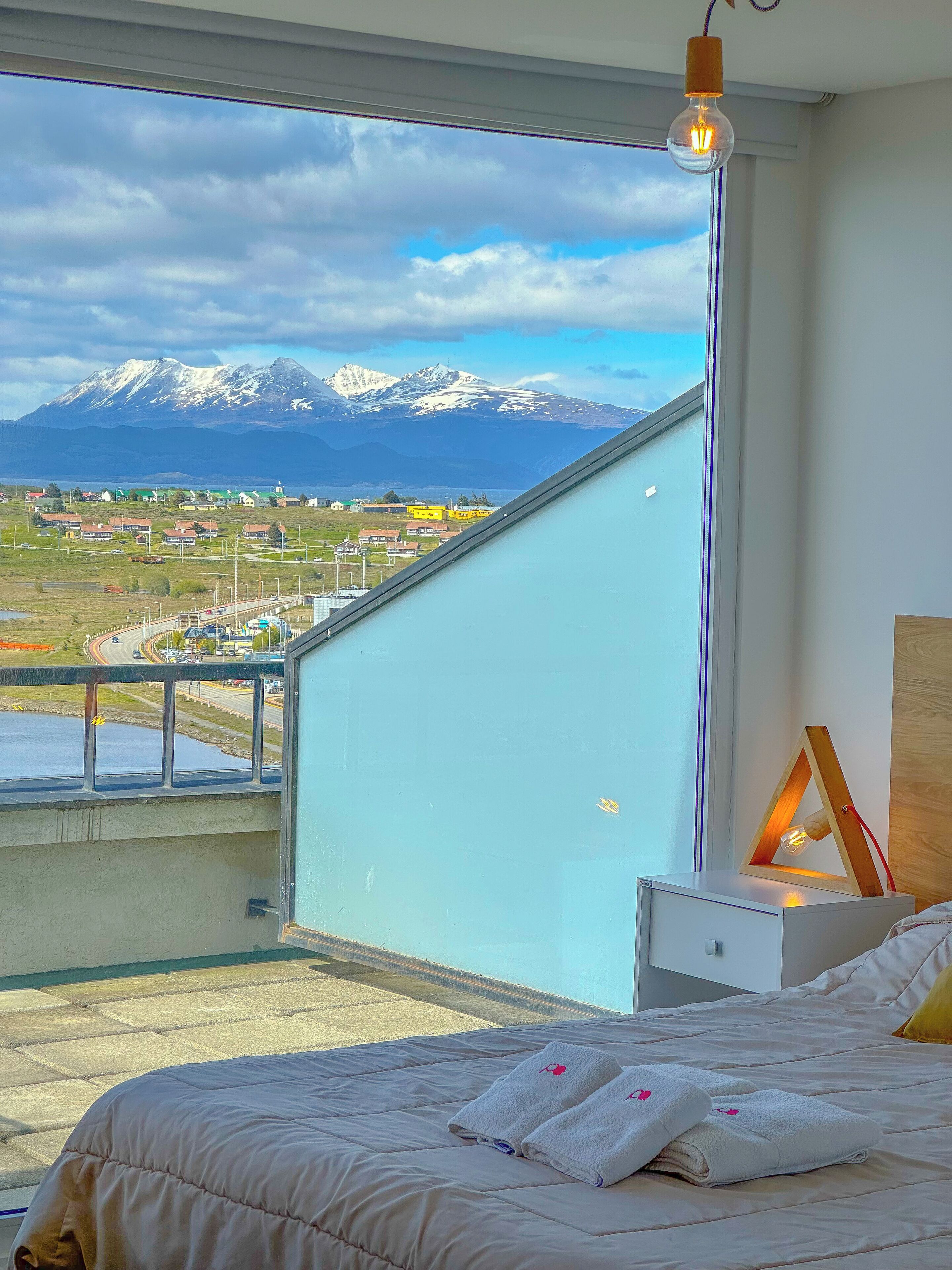 Une chambre à coucher avec un lit, une table de chevet et une vue sur un paysage montagneux.