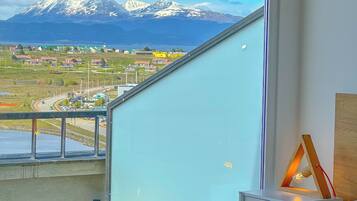 Une chambre à coucher avec un lit, une table de chevet et une vue sur un paysage montagneux.