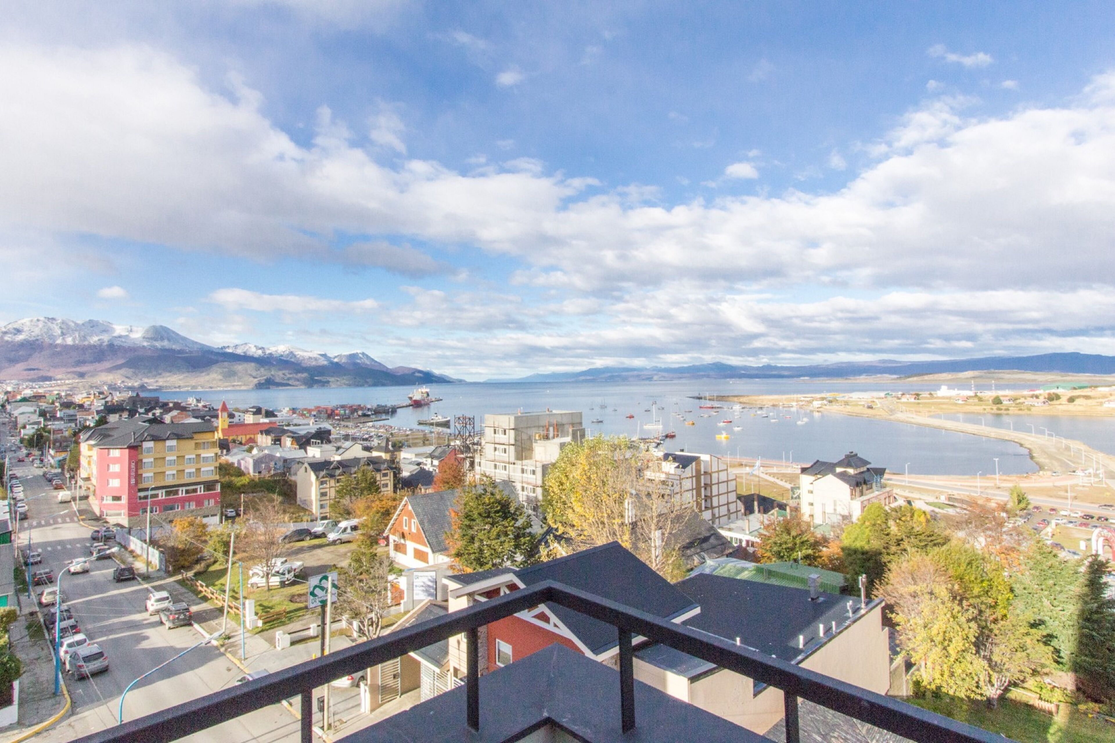 Une ville côtière avec des bâtiments, un port et des montagnes en arrière-plan.