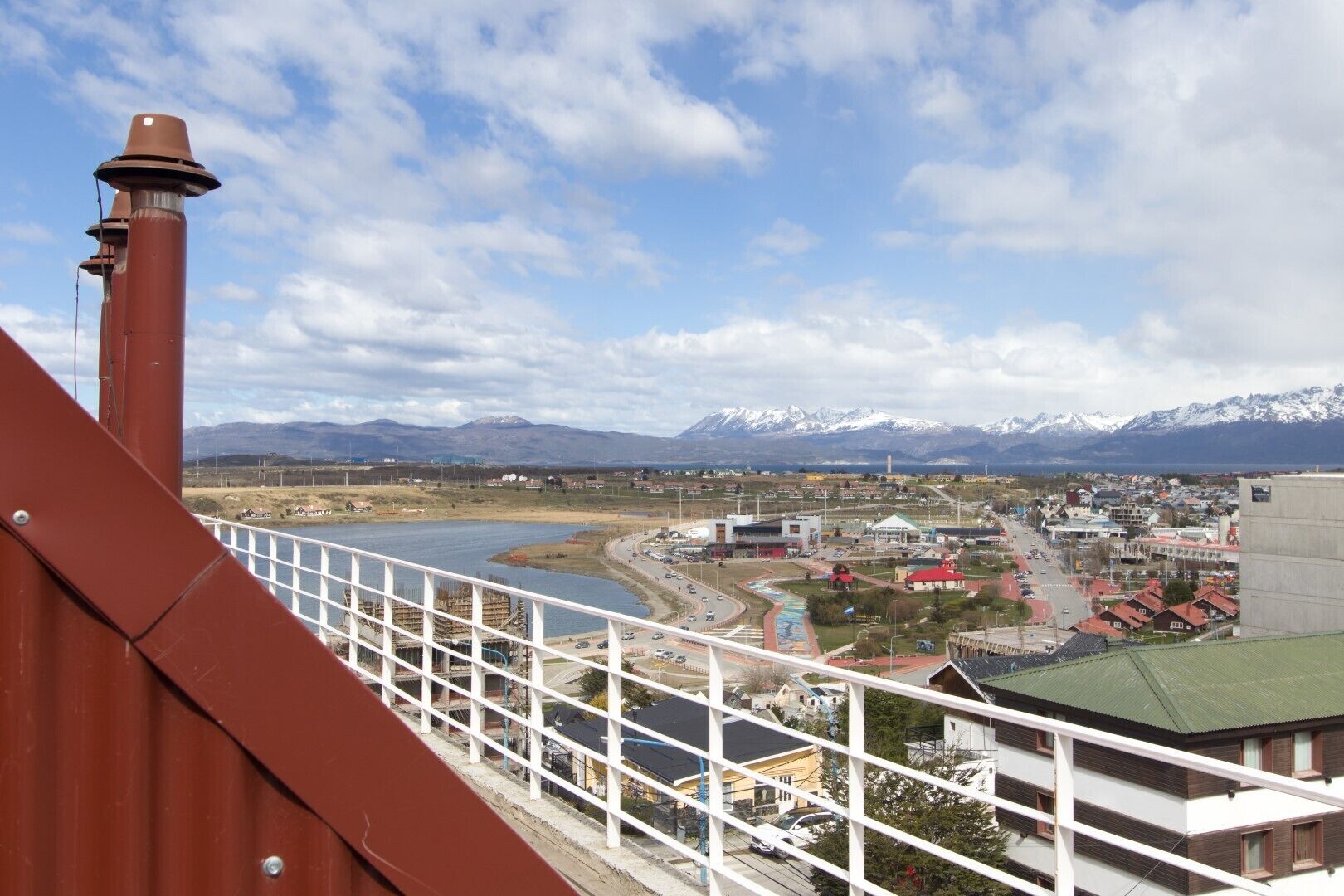 Vista des d'un balcó sobre una vila amb un riu, muntanyes i un pont.