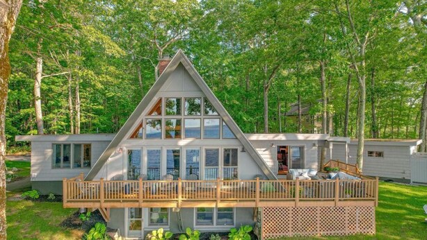 A modern, two-story house with a large deck and a view of the surrounding forest. - The Great Escape - Picturesque Sebago Lake (Raymond)