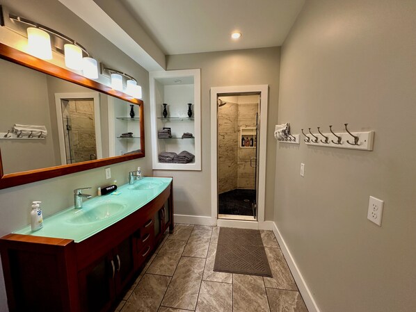 Une salle de bain avec un lavabo en verre, un meuble-lavabo et une douche à l’italienne.