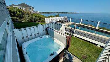 A hot tub on a deck with a view of the sea.