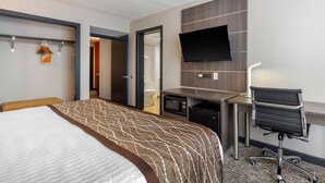 Quarto de hotel com uma cama grande, uma escrivaninha, televisão de tela plana, micro-ondas e uma cadeira.