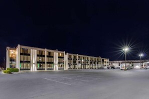 A modern building with a parking lot and multiple vehicles. - VetteCity Hotel (Bowling Green)