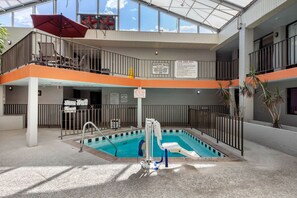 An indoor swimming pool with a lifeguard chair, a pool area rule sign, and a no children warning sign. - VetteCity Hotel (Bowling Green)