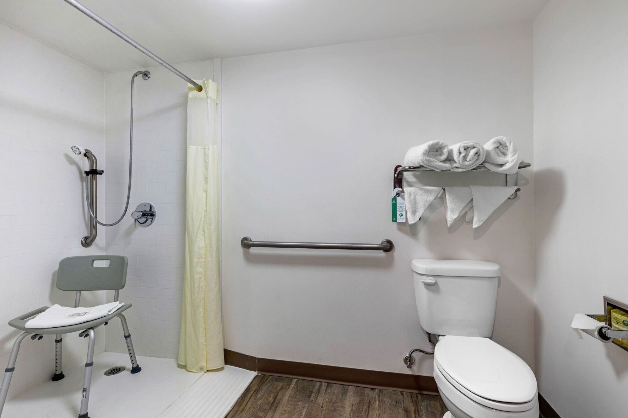 Un baño con ducha, inodoro y barra de apoyo.