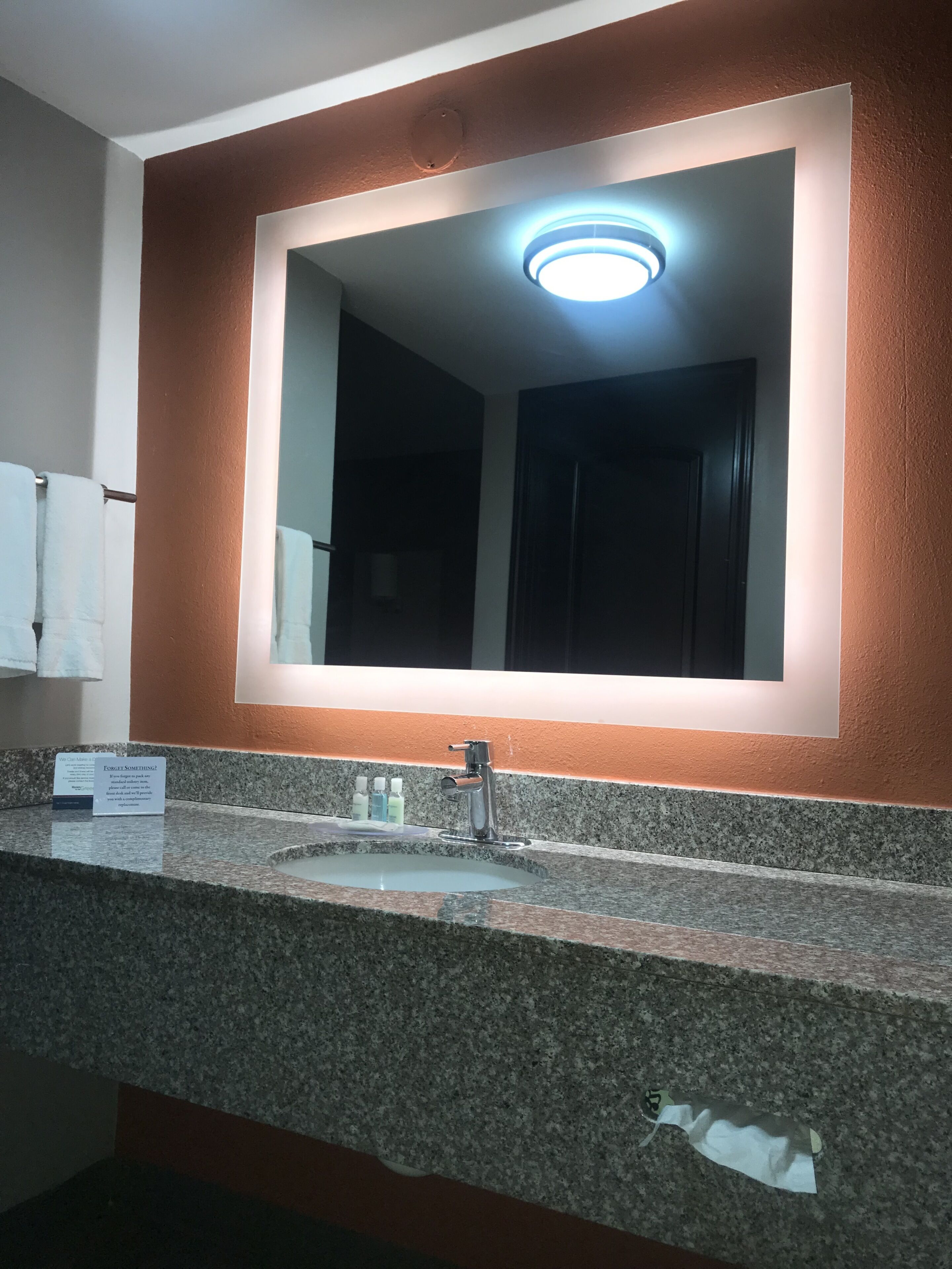 A bathroom with a granite countertop, a sink, a mirror, and a towel rack.