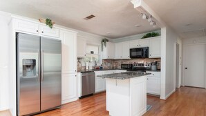 Een moderne keuken met witte kastjes, roestvrijstalen apparatuur en een centraal eiland.