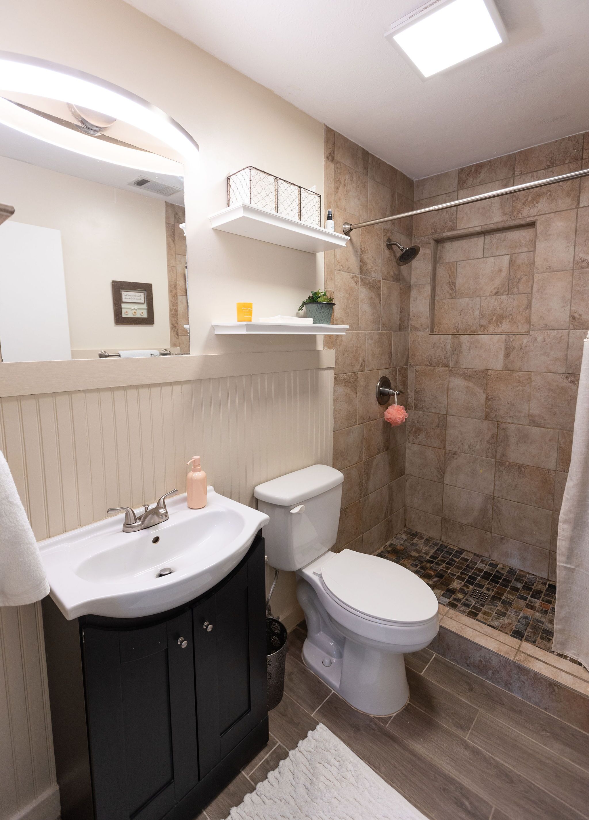 A modern bathroom with a white sink, black cabinets, a white toilet, and a shower area with a glass door.