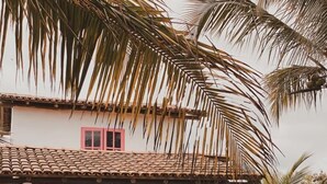 A two-story house with a tiled roof, red doors, and a hammock on the porch. - Pousada Vila Rosa (Porto Seguro)