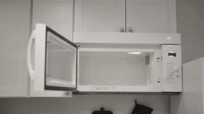A white microwave oven with a digital control panel, installed in a kitchen with white cabinets. - Keizer Valley Estate I 3BR Family Stay Near Salem Oregon (Keizer)