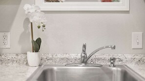 A kitchen sink with a modern faucet, a potted orchid, and a marble countertop. - Keizer Valley Estate I 3BR Family Stay Near Salem Oregon (Keizer)