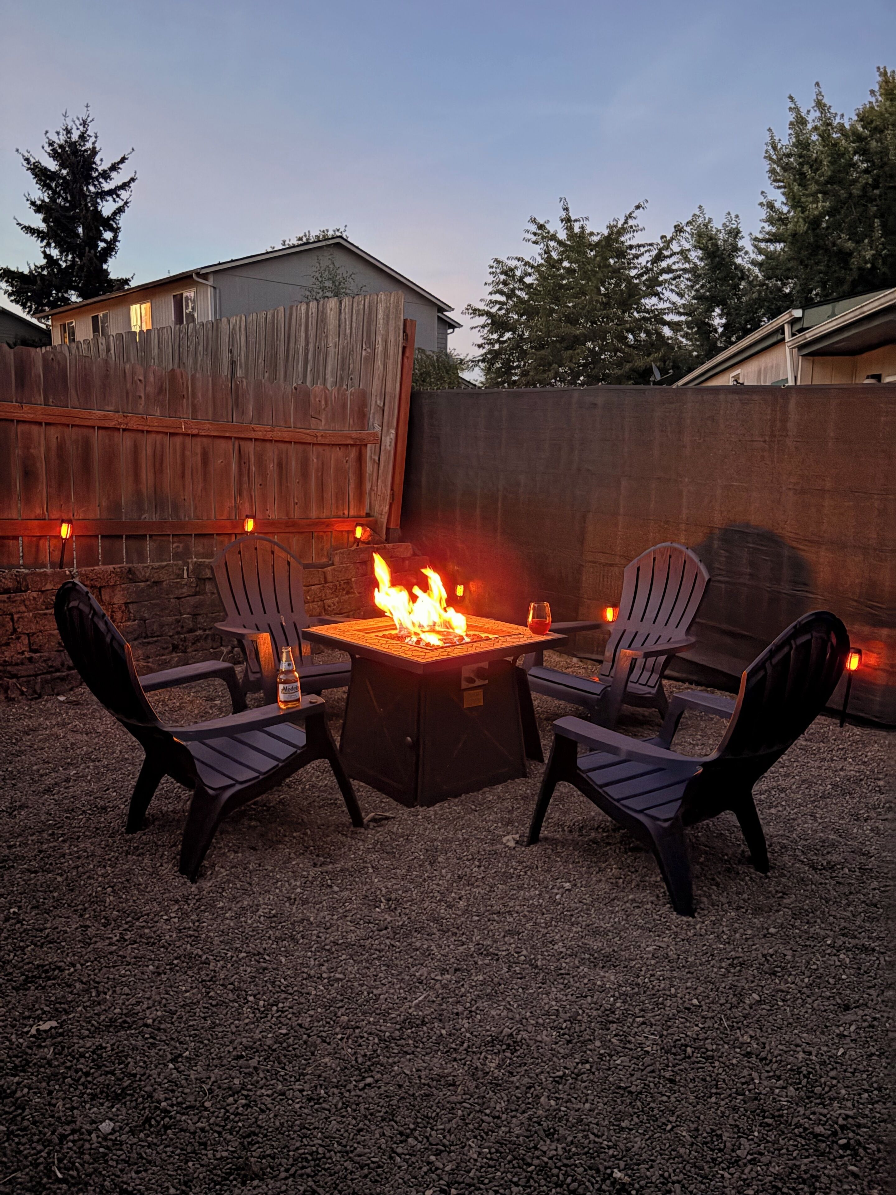 An outdoor seating area with a fire pit, two chairs, and a table.