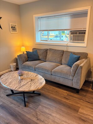 A living room with a sofa, a round coffee table, a lamp, and a window with blinds. - Keizer Valley Estate I 3BR Family Stay Near Salem Oregon (Keizer)