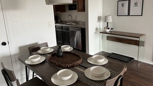 A dining area with a wooden table set for four, a woven placemat, and a pendant light. - Modern Jewel : No Stairs : 3 bedrooms : Sleeps 6 : Pool Open : Views (Branson)