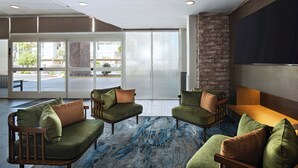 A lobby with a seating area, a stone accent wall, and a large window. - Fairfield by Marriott Inn & Suites Phoenix West Chandler (Phoenix)