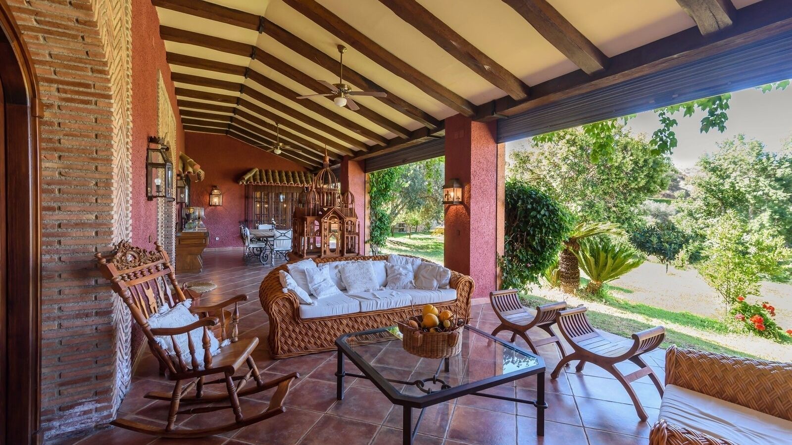 A covered patio with wicker furniture, a sofa, and a dining table.