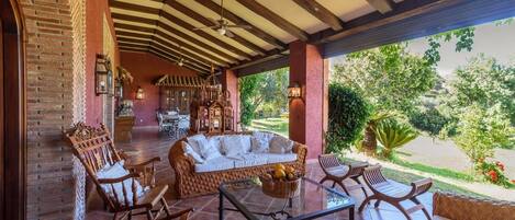 A covered patio with wicker furniture, a sofa, and a dining table.